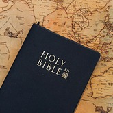 An open Holy Bible resting on a world map, representing evangelism and witness training
